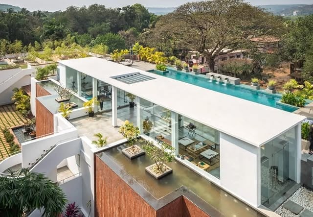 Aerial view of a long white modernist apartment block with a rooftop-level pool